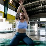 Focused gymnast in a sports hall performing exercises on a mat.